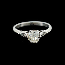 Load image into Gallery viewer, A diamond solitaire ring in platinum, on a black background