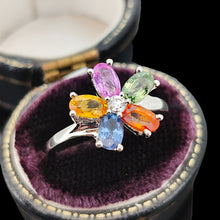 Load image into Gallery viewer, A multi-coloured gemstone flower shaped ring in white gold, in a ring box, on a black background