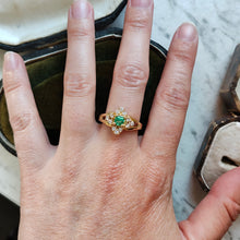 Load image into Gallery viewer, An emerald and diamond compass set cluster ring in yellow gold with split shoulders, modelled on a hand