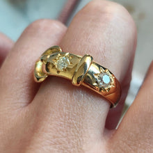 Load image into Gallery viewer, A yellow gold buckle band ring with two diamonds, modelled on a hand