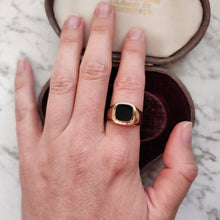 Load image into Gallery viewer, A cushion shaped onyx signet ring in yellow gold, modelled on a hand