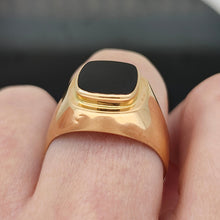 Load image into Gallery viewer, A cushion shaped onyx signet ring in yellow gold, modelled on a hand