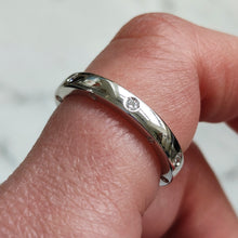 Load image into Gallery viewer, A round diamond set wedding band in white gold, modelled on a hand