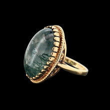 Load image into Gallery viewer, An oval moss agate ring in yellow gold, on a black background