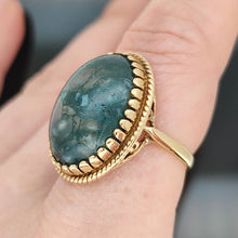 Load image into Gallery viewer, An oval moss agate ring in yellow gold, modelled on a hand