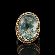 Load image into Gallery viewer, An oval moss agate ring in yellow gold, on a black background