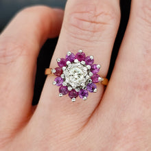 Load image into Gallery viewer, A circular ruby and diamond cluster ring in yellow and white gold, modelled on the ring finger of a hand
