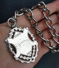Load image into Gallery viewer, A silver Albert watch chain with large oval links, two lobster clasps, a T-bar and a shield shaped fob medal, held in a hand
