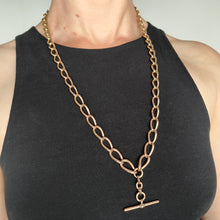 Load image into Gallery viewer, A large link Albert chain necklace in rose gold with a T-bar, modelled by a woman wearing a black top
