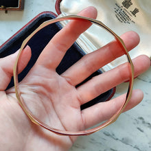Load image into Gallery viewer, A rose gold solid slave bangle bracelet, held in a hand
