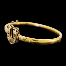 Load image into Gallery viewer, A yellow gold horseshoe bangle bracelet with rubies and diamonds, on a black background
