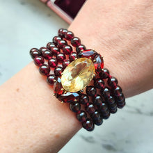 Load image into Gallery viewer, A five row round garnet bead bracelet with a citrine and garnet clasp in yellow gold, modelled on a wrist
