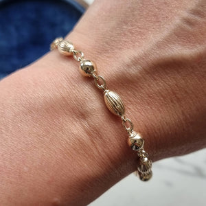 Gold bracelet on a wrist with a blurred background