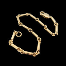 Load image into Gallery viewer, A yellow gold tube link bracelet with lobster claw clasp, on a black background
