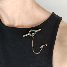 Load image into Gallery viewer, A bar brooch in yellow gold with an oval cabochon banded agate centre, modelled on a black top

