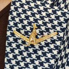 Load image into Gallery viewer, A boomerang shaped brooch with a kangaroo reading BEST WISHES, in yellow gold, modelled on the lapel of a houndstooth pattern jacket
