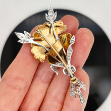 Load image into Gallery viewer, A two tone gold flower brooch with diamonds, held in a hand
