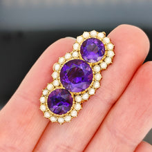 Load image into Gallery viewer, A yellow gold pearl and amethyst brooch, held in a hand
