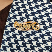 Load image into Gallery viewer, A yellow gold brooch with the word BABY written in pearls, modelled on the lapel of a houndstooth pattern jacket
