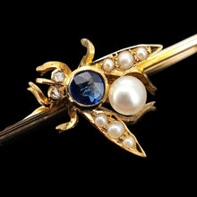 Load image into Gallery viewer, Close-up of a yellow gold fly bar brooch with sapphire, pearls and diamond eyes, on a black background
