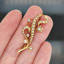 Load image into Gallery viewer, A yellow gold pearl and diamond flower brooch, held in a hand
