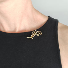 Load image into Gallery viewer, A yellow gold pearl and diamond flower brooch, modelled by a woman wearing a black top
