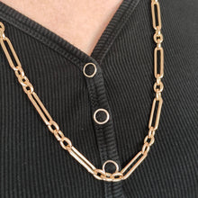 Load image into Gallery viewer, A gold trombone link chain necklace with a lobster claw clasp, modelled by a woman
