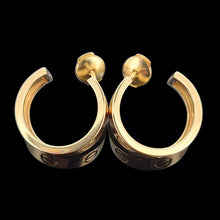 Load image into Gallery viewer, Cartier gold hoop earrings on a black background
