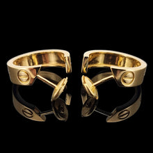 Load image into Gallery viewer, Pair of gold Cartier hoop earrings on a black background
