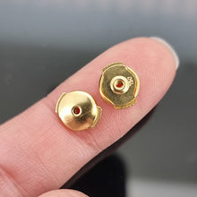 Load image into Gallery viewer, La Pousette gold earring backs held on a finger
