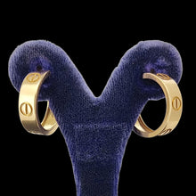 Load image into Gallery viewer, Gold Cartier hoop earrings on a blue stand against a black background
