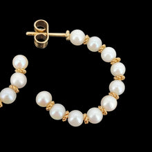 Load image into Gallery viewer, A pair of yellow gold pearl half hoop earrings with butterfly fittings, on a black background

