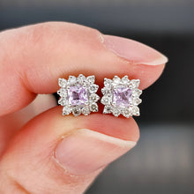 Load image into Gallery viewer, A pair of pink sapphire and diamond cluster stud earrings in white gold, held in a hand
