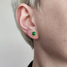 Load image into Gallery viewer, A round jade stud earring in yellow gold, modelled in an ear
