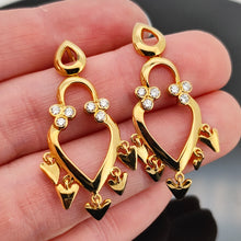 Load image into Gallery viewer, A pair of yellow gold open heart shaped drop earrings with diamonds, held in a hand
