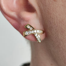 Load image into Gallery viewer, A yellow gold round diamond cross shaped stud earring, modelled in an ear
