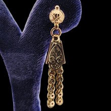 Load image into Gallery viewer, Close-up of a yellow gold fancy engraved tassel drop earring, in an earring stand
