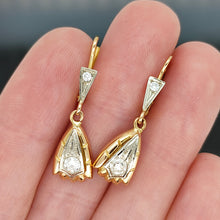Load image into Gallery viewer, A pair of yellow and white gold diamond set drop earrings, held in a hand

