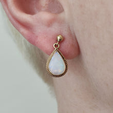 Load image into Gallery viewer, A pear shaped opal drop earring in yellow gold, modelled in an ear
