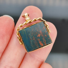 Load image into Gallery viewer, A bloodstone swivel fob in yellow gold, held in a hand
