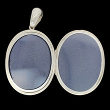 Load image into Gallery viewer, An intricate engraved oval locket pendant in silver, on a black background
