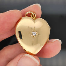 Load image into Gallery viewer, A yellow gold heart shaped locket with a diamond, held in a hand
