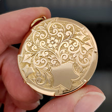 Load image into Gallery viewer, A circular yellow gold engraved locket pendant, held in a hand
