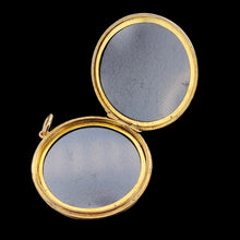 Load image into Gallery viewer, A circular yellow gold locket pendant, open, on a black background
