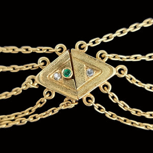 Gold chain necklace with a push-in clasp featuring an emerald and two diamonds on a black background