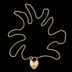 Gold chain necklace with a heart-shaped padlock pendant on a black background