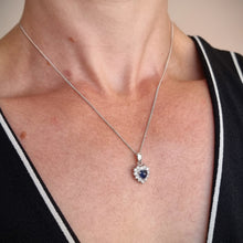 Load image into Gallery viewer, A heart shaped sapphire and diamond cluster pendant, with a curb link chain, modelled by a woman

