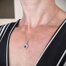 Load image into Gallery viewer, A heart shaped sapphire and diamond cluster pendant, with a curb link chain, modelled by a woman
