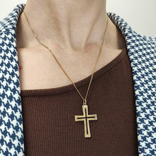 Load image into Gallery viewer, A yellow gold cutout design cross pendant hung on a gold chain, modelled by a woman
