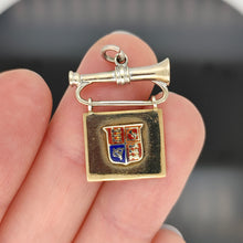 Load image into Gallery viewer, A yellow and white gold flag and bugle charm with an enamel coat of arms, in a hand
